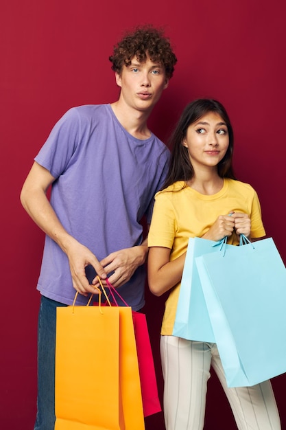 Carino giovane coppia borse colorate shopping divertimento sfondo rosso inalterato