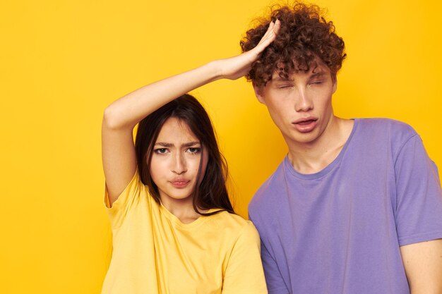 Cute young couple in colorful tshirts posing friendship fun yellow background unaltered