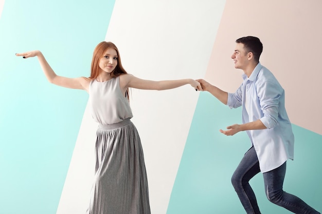 Cute young couple dancing against color wall