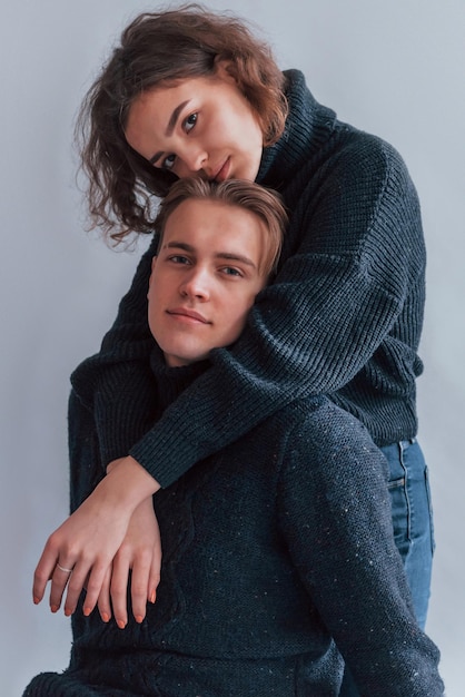 Cute young couple embracing each other indoors in the studio.