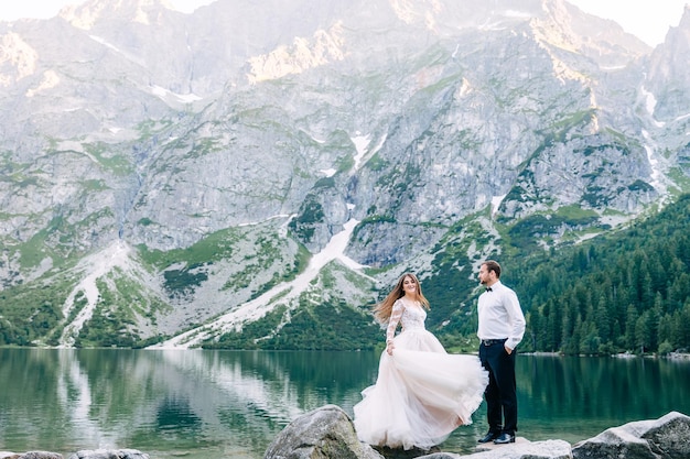 Cute young couple in love spending time in the mountains by the lake