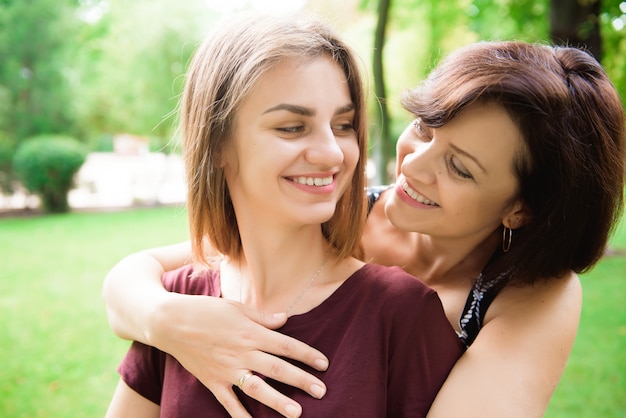 Cute young daughter embracing her mother with love.