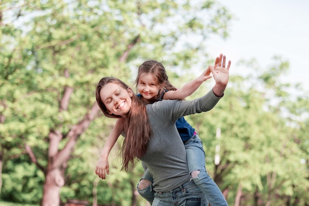 Cute young daughter on a piggy back ride with her mother.concept of happiness