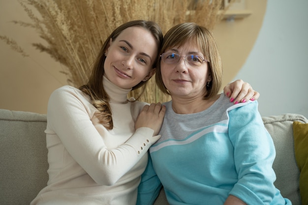 Photo cute young daughter in stylish hipster eyeglasses embracing her mother with love spending day together