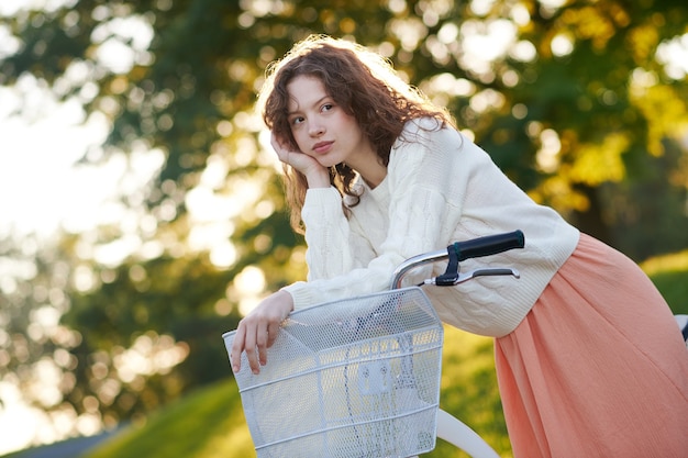 Cute young girl on a bike in the park looking thoughtful