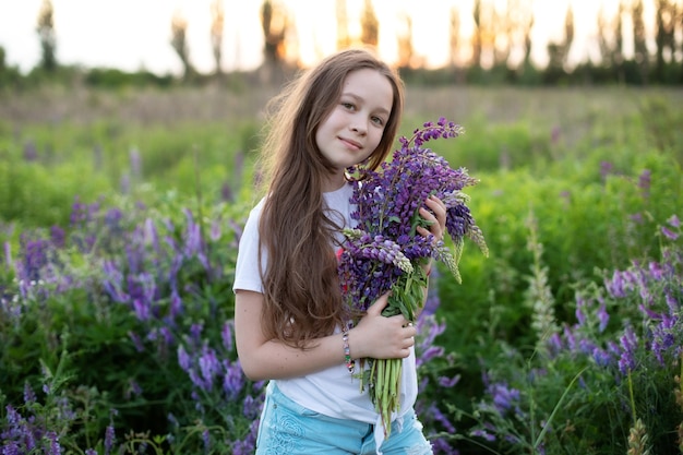 ルピナスのフィールドでかわいい若い女の子花の花束を持っている女の子牧草地で花束ルピナスと子供