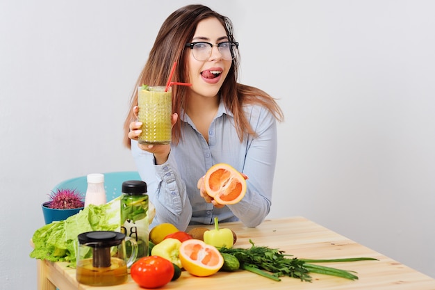 Cute young girl in glasses with a glass of smoothies in hands.