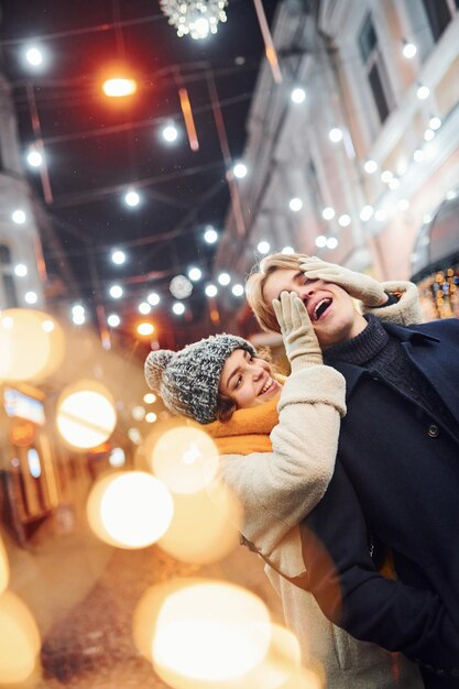 Cute young girl makes surprise to her boyfriend by walking behind him.