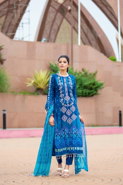 Ragazza carina che indossa un abito blu tradizionale e gioielli per le riprese di moda al monumento del pakistan