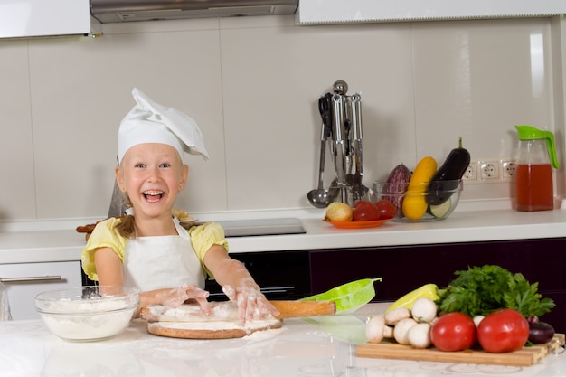 Ragazza carina con un grande sorriso sul viso al lavoro in cucina