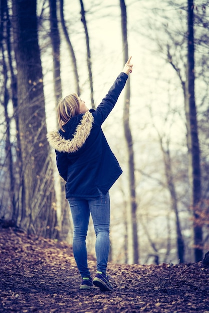 Cute young girl with blue parker is standing in the forest autumn time