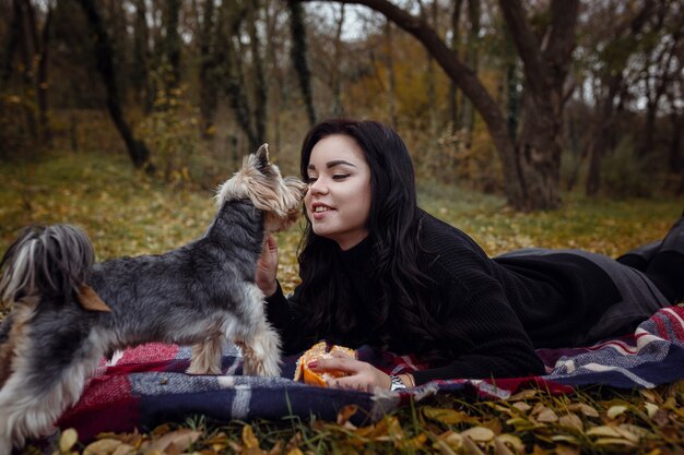 Cute young girl with yorkshire terrier dog in the park in autumn. concept of care and friendship