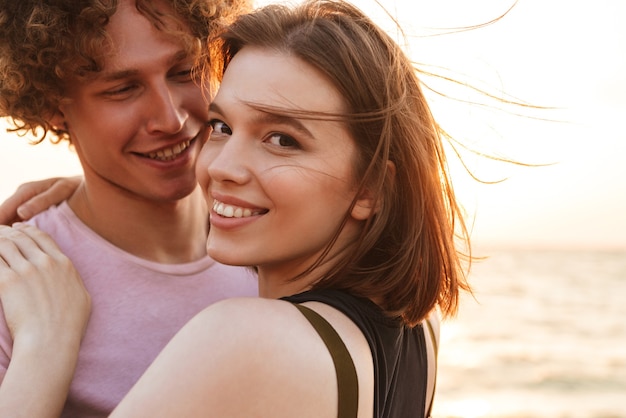 cute young happy loving couple hugging outdoors on the beach Woman looking camera.