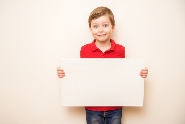 Cute young happy preschooler boy holding up blank sign with room for copy isolated on white