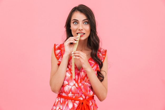 Cute young lady posing isolated wall eat candy.