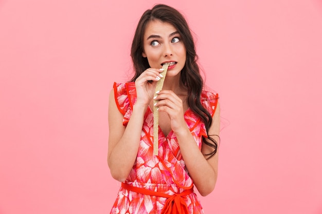 Cute young lady posing isolated wall eat candy.