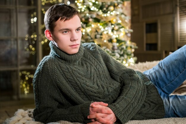 Cute young man in a knitted sweater resting on the sofa