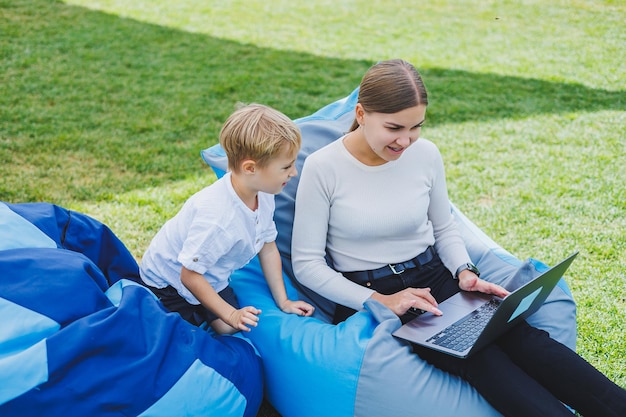 귀여운 젊은 엄마와 아들이 노트북을 보고 있다 행복한 가족 엄마와 아들이 공원에서 쉬고 있다 출산 휴가 중인 여성