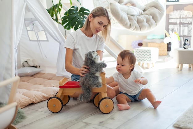 Cute young mother with her little daughter are playing in the playroom with toys Motherhood