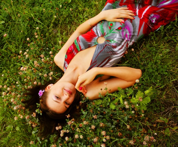 Cute young redhead female lying on grass field at the park