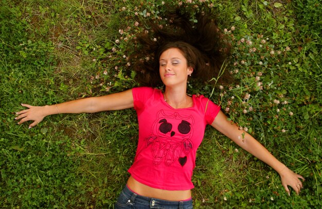 Cute young redhead female lying on grass field at the park