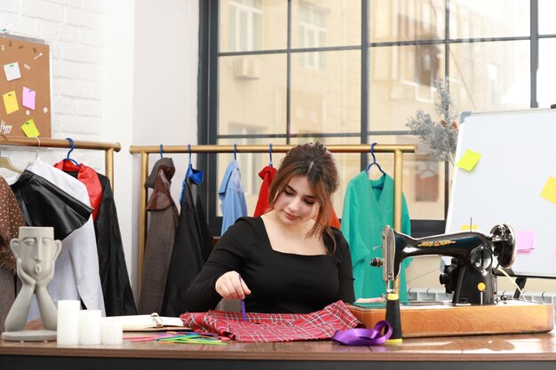 Cute young tailor sewing clothes at the atelier