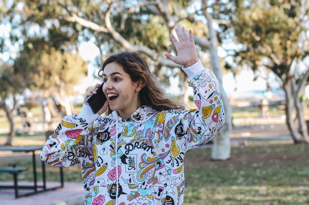 Ragazza sveglia dell'adolescente che parla con gli amici per telefono. ragazza della scuola felice di vedere i suoi amici