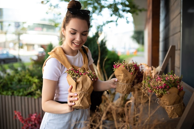 Cute young woman holding her favorite flowers in a street garden shop