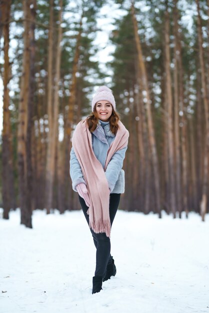 Cute young woman is playing with snow in the forest. Winter lifestyle happiness emotions nature. Christmas, New year.