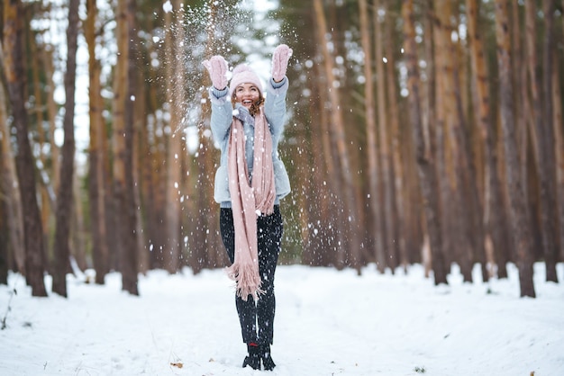 Cute young woman is playing with snow in the forest. Winter lifestyle happiness emotions nature. Christmas, New year.