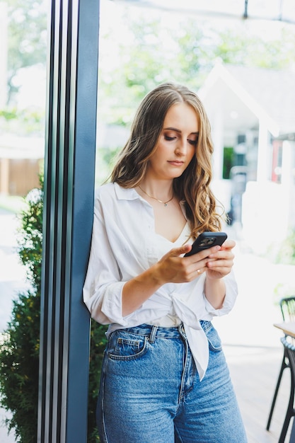 cute young woman in jeans and a white casual shirt is talking on the phone Video communication via telephone Remote freelance work