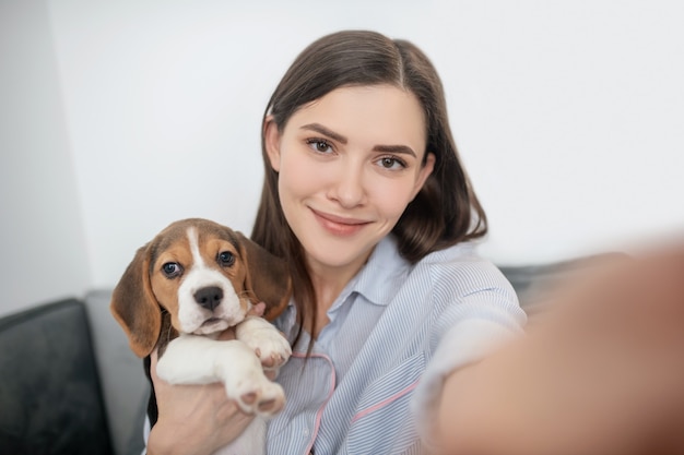 子犬と一緒に自分撮りをするかわいい若い女性