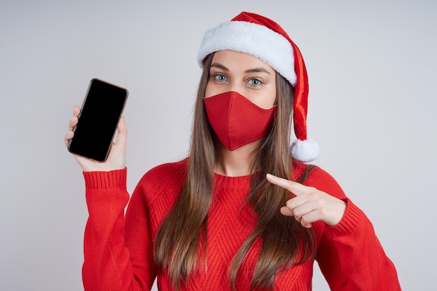 A cute young woman in a Santa hat, in protective mask