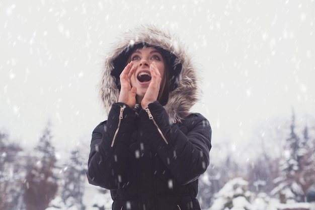 Cute young woman under showflakes in winter.