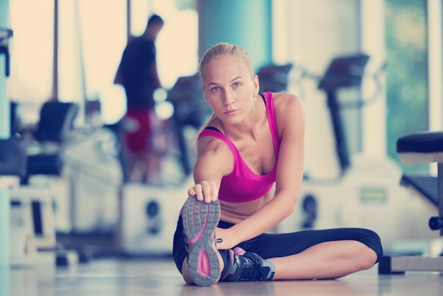 Cute young woman stretching and warming up for her training at a gym