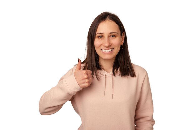 Cute young woman wearing sweatshirt is showing thumb up like gesture