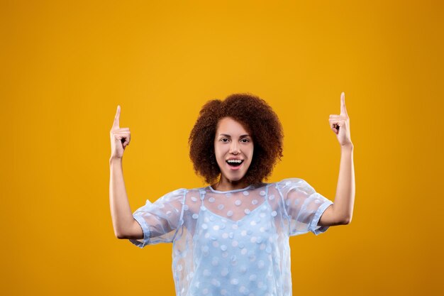 Cute young woman in a white blouse pointing her finger up