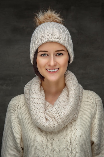 Симпатичная молодая женщина в белом свитере и зимней шапке.