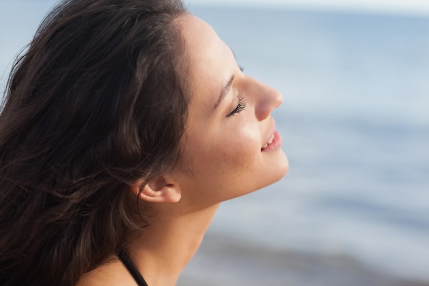 Giovane donna sveglia con gli occhi chiusi alla spiaggia