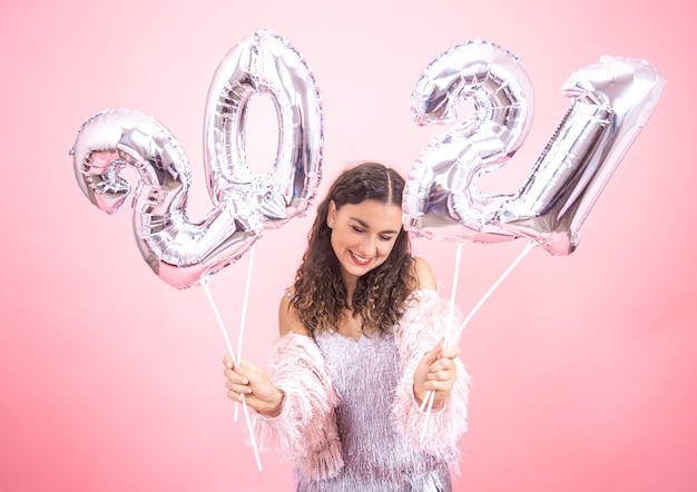 Carina giovane donna con un sorriso in un abito festivo, con palloncini d'argento per il concetto di nuovo anno