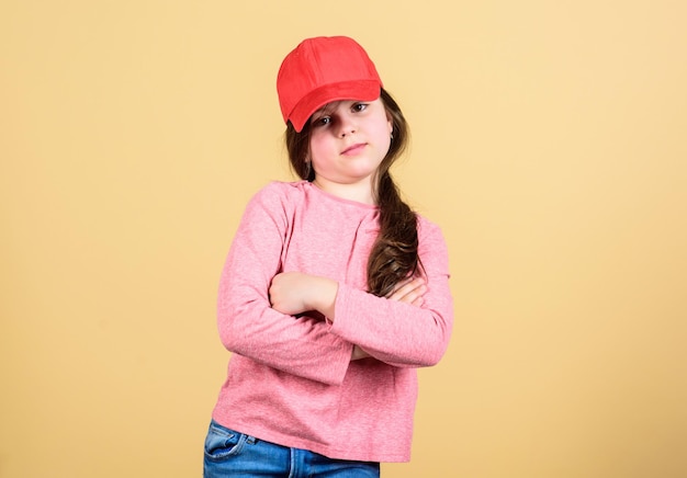 Cutie in cap moda moderna accessorio alla moda moda per bambini sensazione di sicurezza con questo berretto ragazza carina bambino indossa un berretto o un cappello snapback sfondo beige bambina indossa un berretto da baseball luminoso