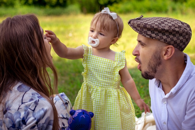 公園での家族のピクニックで、かわいい赤ちゃんの女の子が母親の鼻に触れる