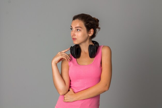 Cutie young woman with headphones in studio on grey wall