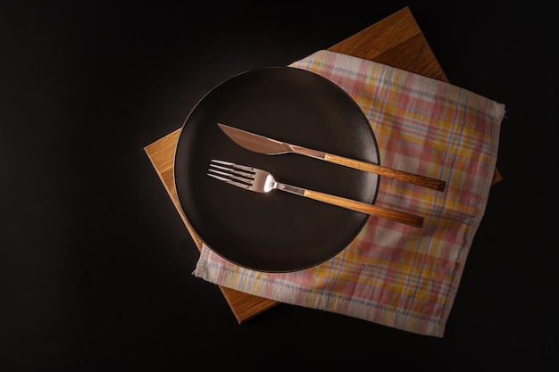 Cutlery on a black plate isolated on a black background top viewflat lat