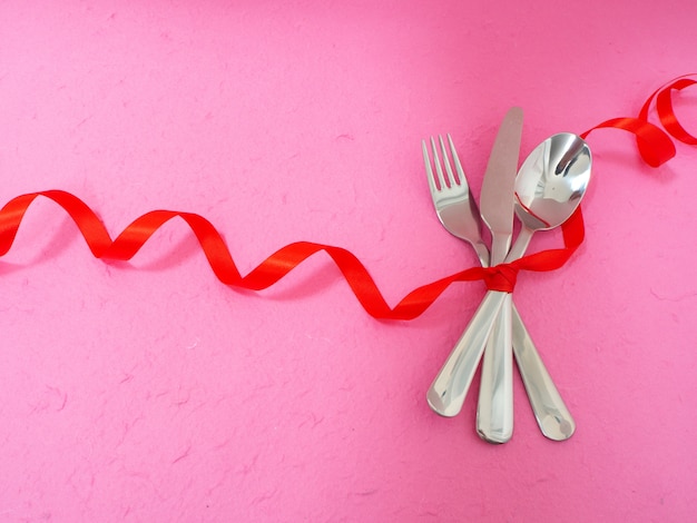 Cutlery and hearts on pink table