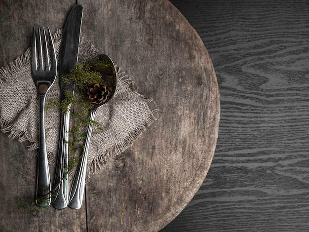 Cutlery Knife fork spoon green branch on a old wooden table toned Top view flat lay copy space