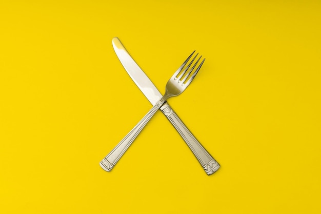 Cutlery lying on a yellow background minimalism