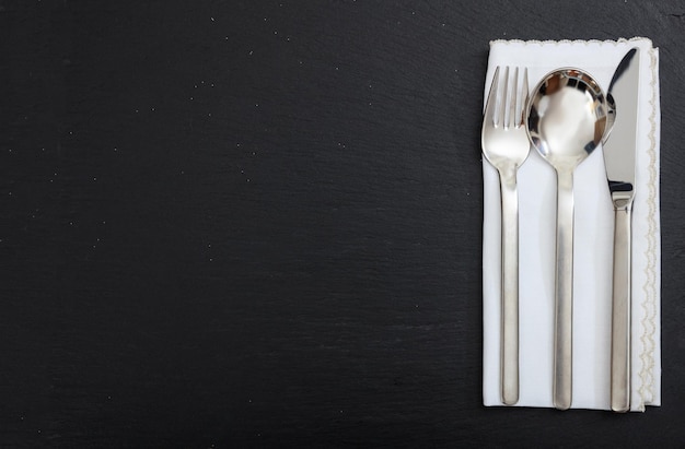 Cutlery and napkin on black background