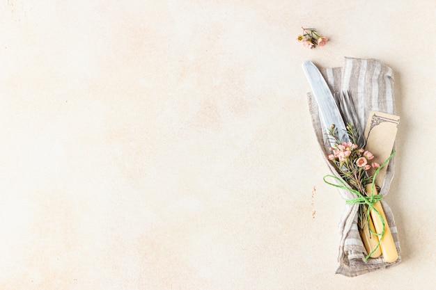 Photo cutlery set and beautiful pink flowers on light stone table