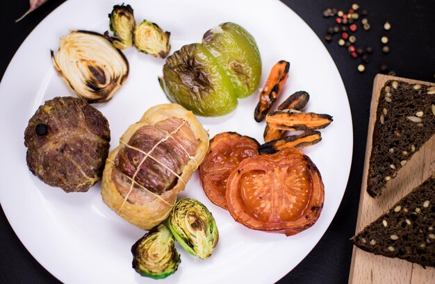 白いプレートと暗い背景にグリル野菜と肉からカツ